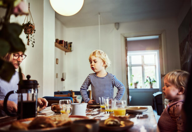 Två små barn och vuxen sitter vid frukostbord